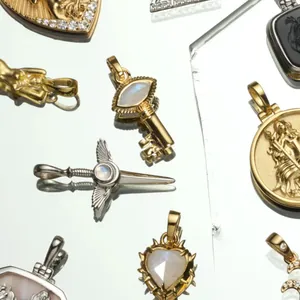Pendentifs dorés 18K avec cœur, clé d'ange et étoile sur une surface miroir élégante