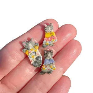 Three hand-painted cat pendants in ceramic style with 18K gold rings on fingertips