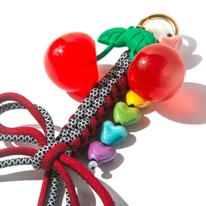 Handmade cherry keychain with colorful heart beads and green leaves on white background