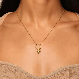 Detail van de gouden hartjes hanger met kralenrand en ring op een gebreide trui
