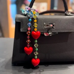 Detail of colorful acrylic beaded bag charm featuring three vibrant red heart pendants