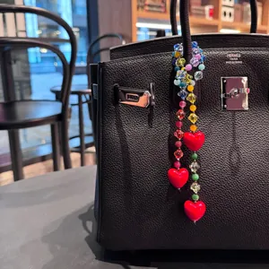Colorful acrylic beaded bag charm with red heart pendants on a black leather handbag