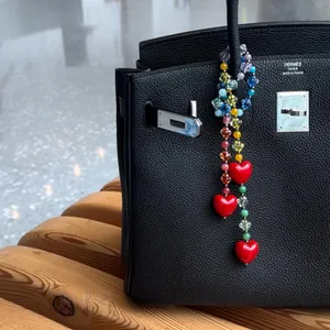 Colorful acrylic beaded bag charm with vibrant red heart pendants on a black leather bag