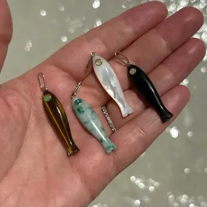 Detalle de colgantes de pez en oro de 14k con ojo de tigre, jade, nácar y ónix