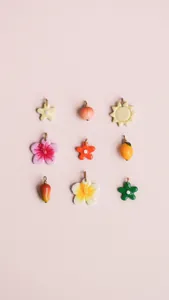 Detailed grid of nine enamel pendants featuring colorful floral, fruit and sun motifs