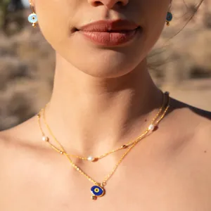 Detail view of 18k gold plated double layer necklace with pearl and blue evil eye charms