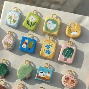 Hand-painted clay pendants with floral, animal, and house designs in 18K gold plating