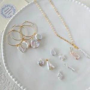Baroque pearl jewelry set with gold hoop earrings and pendant necklaces on a white plate
