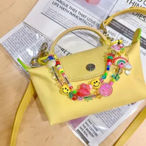 Macro view of a mini yellow handbag with colorful smiley face and heart beaded charms