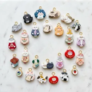 Handcrafted ceramic cat and rabbit pendants with gold rings on white marble background