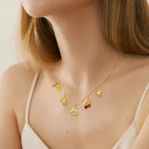 Gros plan d'un collier doré avec pendentifs fruits tropicaux et étiquette Goodness