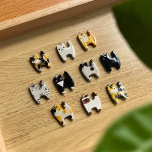 Detailansicht verschiedener süßer Katzenanhänger für DIY-Schmuck auf einem Holztablett