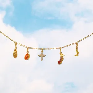 Collier doré avec pendentifs de fruits tropicaux et zircons sur fond de ciel bleu