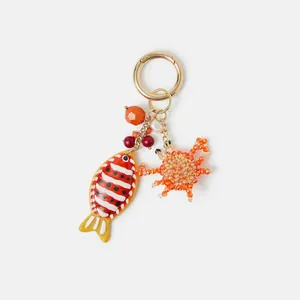 Summer ocean themed keychain with enamel fish and crab charms on a golden metal ring