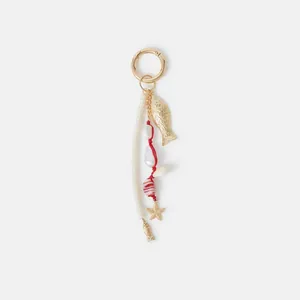 Detail of marine-style bag charm with gold fish, pearls, and red woven rope accents