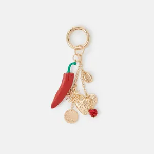 Macro view of golden keychain featuring red enamel chili and textured heart charms