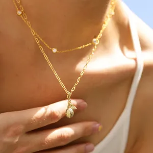 Gros plan du collier doré multi-rangs avec pendentif ananas et accents en zircon