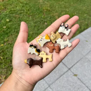 Nahaufnahme von acht diversen Cartoon-Hundeanhängern in der Hand vor Gartenhintergrund