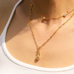 Détail d'un collier double épaisseur doré avec zircons et pendentif goutte texturé