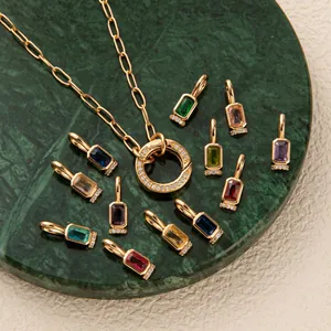 Golden chain necklace with 12 colorful birthstone pendants on green marble display