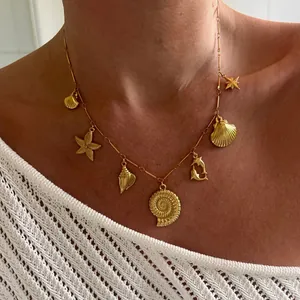 Gold ocean themed necklace featuring starfish and seashell pendants on a female model