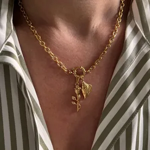Detail of gold nautical necklace with rose and conch charms on a striped shirt