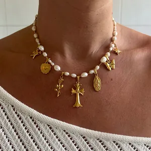 Baroque pearl necklace detail with golden gothic cross and religious charms worn on neck