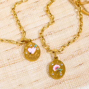 Close-up of gold-plated pendant necklaces with pink enamel flowers and love engraving