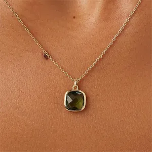 Collier chaîne dorée avec pendentif carré en pierre vert olive porté par un mannequin