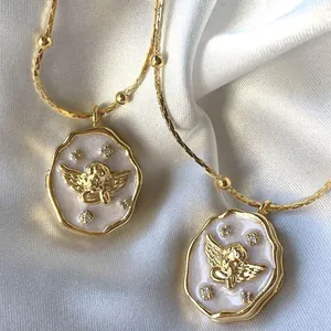 Vintage gouden engel medaillon hanger met parelwitte inleg op zijden achtergrond