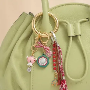 Gros plan d'un bijou de sac coloré avec motifs roses et pompons sur un sac en cuir