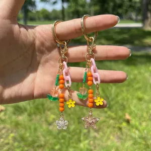 Flower beaded keychain with 18K gold plated clasp and rhinestones on grass background