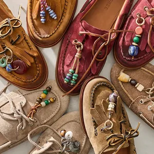 Detailansicht der bunten Perlen, Quasten und Metallringe auf Wildleder-Loafers