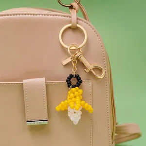 Handgefertigter Bienen-Taschenanhänger mit goldenem Karabinerverschluss an einer Ledertasche