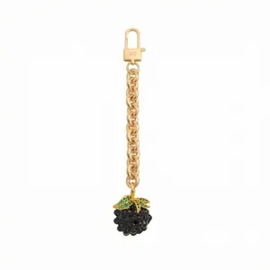 Detailed macro of golden blackberry keychain with green gems and engraved lobster clasp
