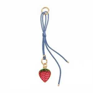Detail of red strawberry heart charm with green leaves on blue braided cord with gold clasp