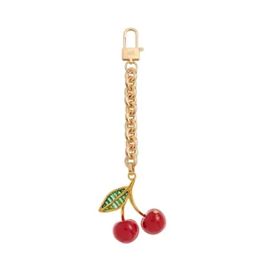 Elegante kersentasbedel met gouden metalen ketting en rode vruchten hangers
