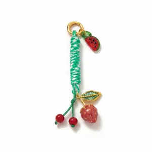 Macro detail of handmade braided rope keychain with strawberry and watermelon charms