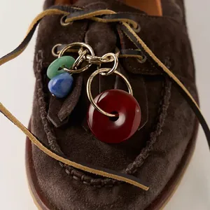Ethno-Schuhanhänger mit bunten Perlen und Steinen an braunen Wildleder-Bootsschuhen