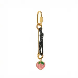 Detail of pink peach pendant with woven rope and golden carabiner for bag charm