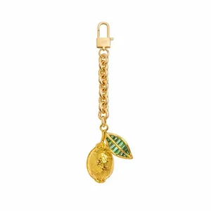 Gedetailleerde close-up van een gouden citroen sleutelhanger met groene bladeren en ketting