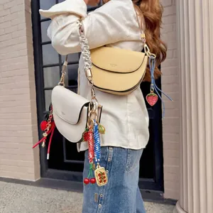 Minimalist leather saddle bag with colorful strawberry and cherry charm accessories