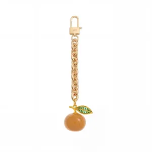 Detail van vintage koperen tassenhanger met oranje bol en groen kristallen blaadje