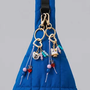 DIY 18K gold plated keychain with cute unicorn and dog charms on a blue quilted bag