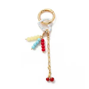 Detail of DIY keychain with gold spring clasp, colorful beads and cherry pendant