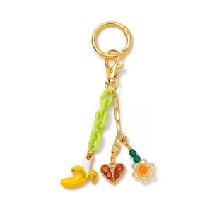 Detailansicht kreativer goldener Schlüsselanhänger mit Banane, Herz und Blumenanhänger