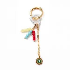Detail of 18K gold-plated keychain featuring colorful beads and a kiwi slice pendant