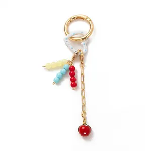 Detail of DIY keychain with gold spring clasp, colorful beads and strawberry pendant