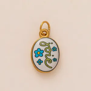 Detailed close-up of oval enamel pendant with Love lettering and blue flower motifs