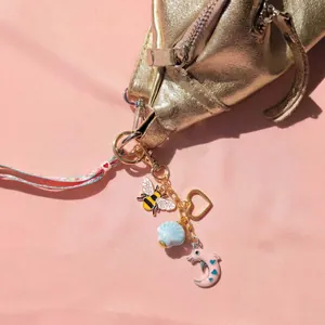 Porte-clés DIY avec breloques abeille, cœur et dauphin sur sac doré et fond rose